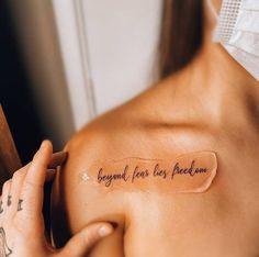 a woman with a tattoo on her shoulder that says, beyond fear lies reason behind