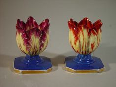 two colorful vases sitting on top of blue bases