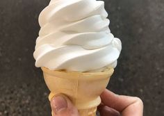 a hand holding an ice cream cone filled with whipped cream