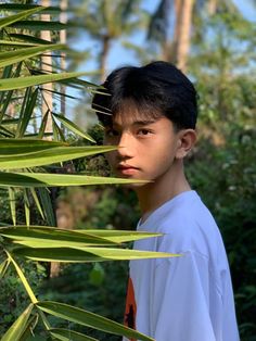 a young man is standing in front of some palm trees and looking at the camera