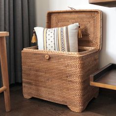 a wicker basket with two pillows on it and a wooden table in the background