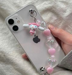 a person holding an iphone case with charms attached to it