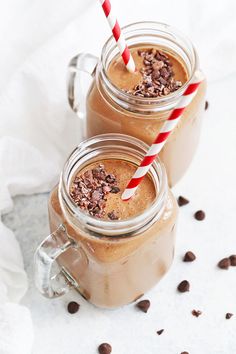 two mason jars filled with chocolate milkshakes and topped with candy canes next to coffee beans