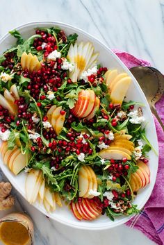 a white plate topped with sliced apples and pomegranate on top of a table