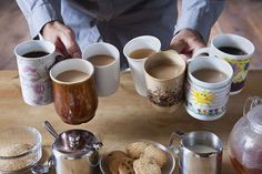 there are many coffee cups on the table with their lids open and some cookies in front of them