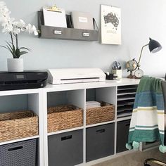 a desk with some baskets on it and a printer in the corner next to it