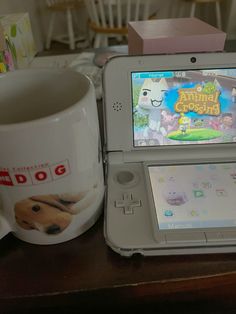 a nintendo wii game system sitting on top of a table next to a coffee mug