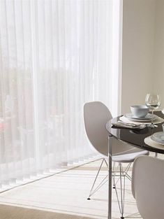 a dining room table with white chairs and plates on it