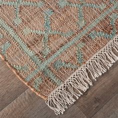 an area rug with fringes on the floor and wood floors in front of it