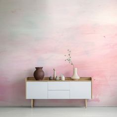 two vases are sitting on a dresser against a pink and white wall with a painted background