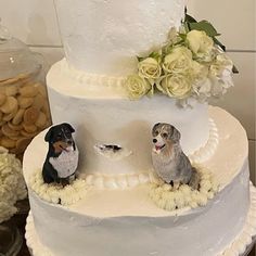 there is a wedding cake with two dogs on the top and flowers in the bottom