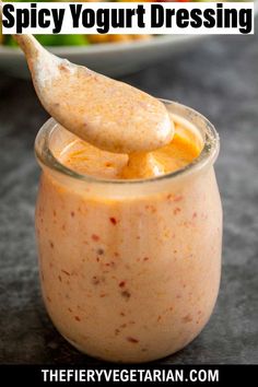 an orange smoothie in a glass with a spoon sticking out of it