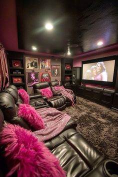 a home theater with black leather couches and pink throw pillows on the carpeted floor