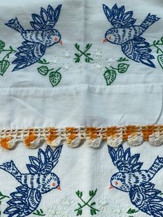 an embroidered piece of cloth with flowers and leaves in blue, green, orange and white