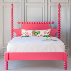 a bed with pink headboard and foot board in front of a white paneled wall