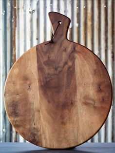 a large wooden cutting board sitting on top of a metal table next to a wall