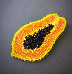 an orange and yellow beaded brooch with a black bat on it's side