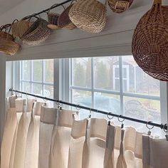 the curtains are lined up in front of the window with wicker baskets hanging from them