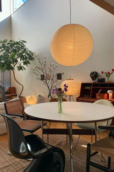 a white table with chairs around it and a vase on the table in front of it