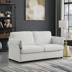 a white couch sitting in a living room next to a book shelf filled with books