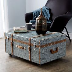 a blue suitcase sitting on top of a wooden floor next to a chair and coffee table