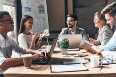 group of business people sitting around a table in an office having a meeting and clapping