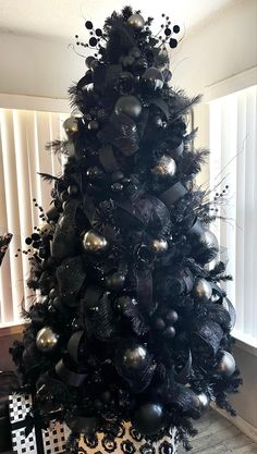 a black christmas tree decorated with silver ornaments