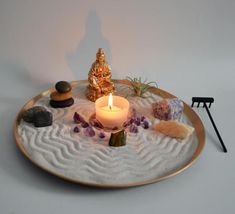 a small buddha statue sitting on top of a plate filled with rocks and other items