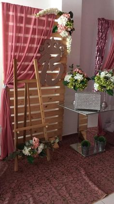 a room with pink curtains and flowers on the wall next to a glass top table