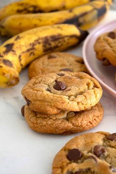 banana cookies with chocolate chips are stacked on top of each other in front of some bananas