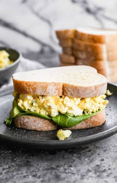 an egg and avocado sandwich is on a plate next to some toasted bread