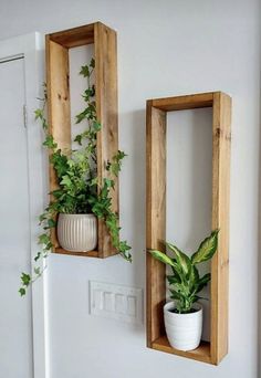 two wooden boxes with plants in them hanging on the wall next to a potted plant