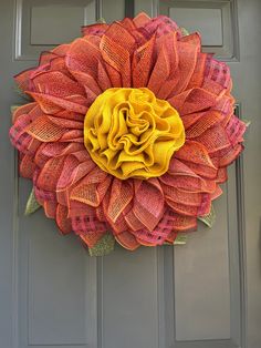 a large orange and yellow flower on the front door of a house with grey doors