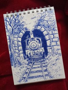 a notebook with a drawing of a train coming out of a tunnel in the woods