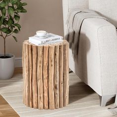 a small wooden table sitting on top of a white rug next to a couch and potted plant