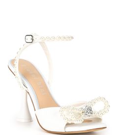 a white high heeled shoe with pearls on the ankle and an embellished bow