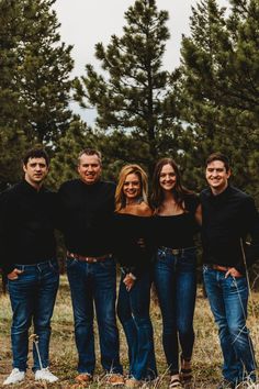 a group of people standing next to each other in front of some trees and grass