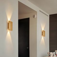 two lights on the wall above a bed in a room with white walls and flooring