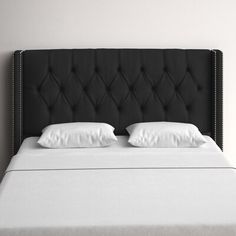 an upholstered black headboard with white linens and pillows on a bed