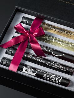 three lip glosses in a gift box tied with a pink ribbon