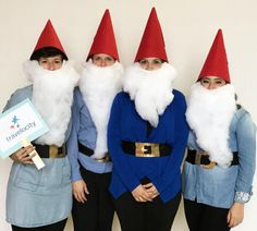 three people dressed as gnomes posing for the camera with a sign in front of them