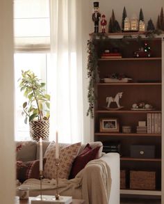 a living room filled with furniture and a christmas tree on top of a book shelf