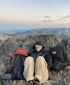 a person sitting on top of a mountain with backpacks