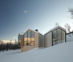 two wooden buildings sitting on top of a snow covered slope