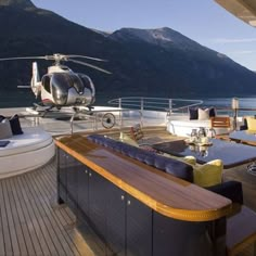 a helicopter sitting on top of a boat next to lounge chairs and an ocean view