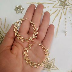 a pair of gold hoop earrings sitting on top of a white table next to a hand