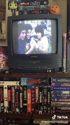 an old television sitting on top of a book shelf filled with books and dvds in front of it