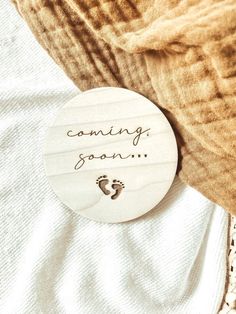 a wooden sign that says, coming soon with a baby's foot on it