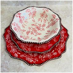 three red and white dishes on a marble counter top with black beaded trim around the edges