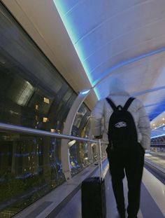 a man is walking down an escalator with his luggage in hand and wearing a backpack